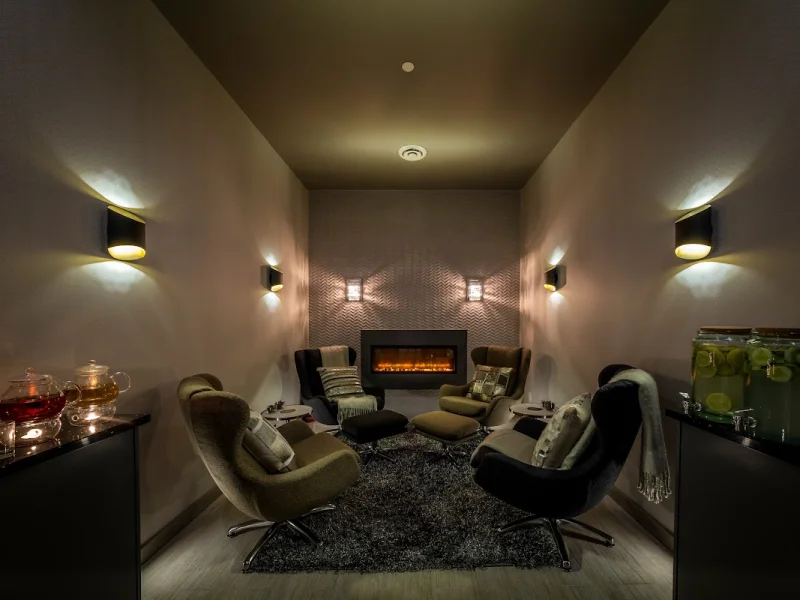 Cozy spa lounge with fireplace, lounge chairs, and calming tea service