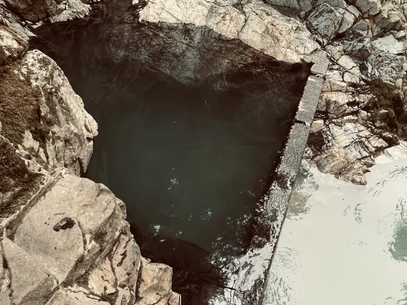 Visitors exploring a narrow rock pool hot spring beside the river