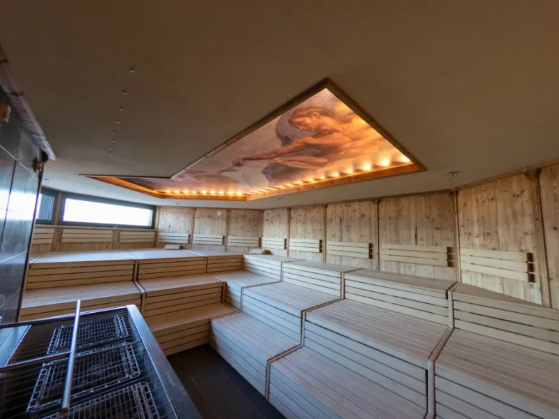 Wood-lined sauna with tiered benches and warm ambient lighting